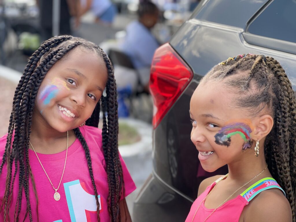 two children with colorful face paint smiling