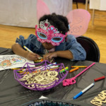 A young girl in a fairy costume drawing at one of TheWash Youth Foundation's community events.